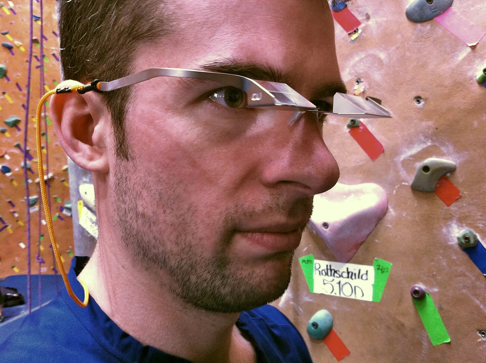 A climber wearing belay glasses whose prism lenses turn the line of sight upward