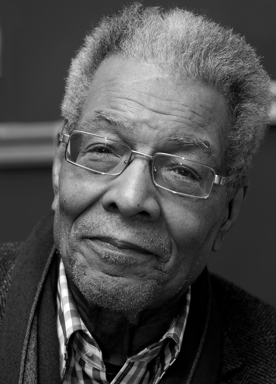 Black and white portrait of a smiling Benjamin Patterson with grey hair and glasses