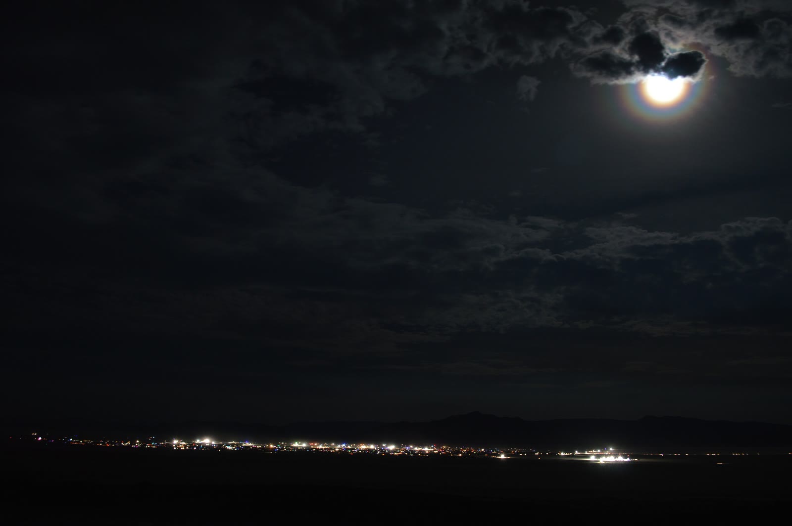 Black Rock City in Nevada's Black Rock Desert at night under a moon corona