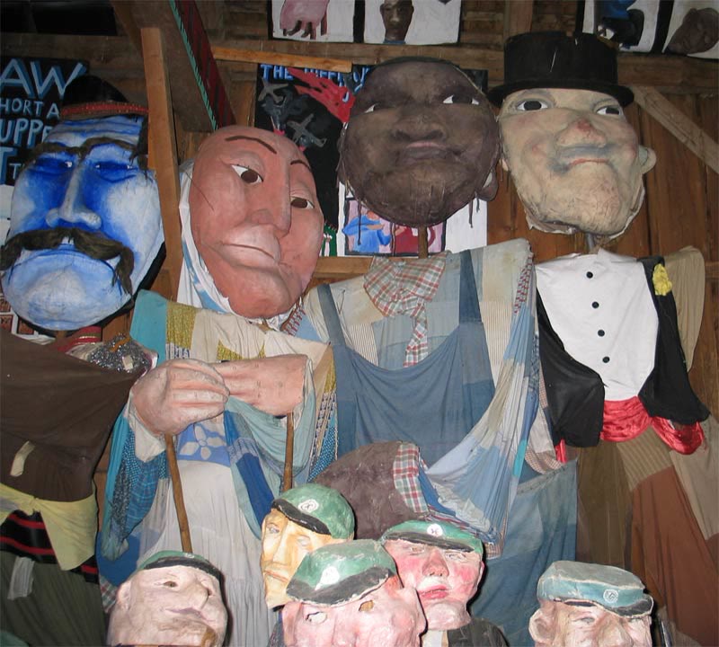 Large painted puppet heads and figures crowded together in the Bread and Puppet Museum