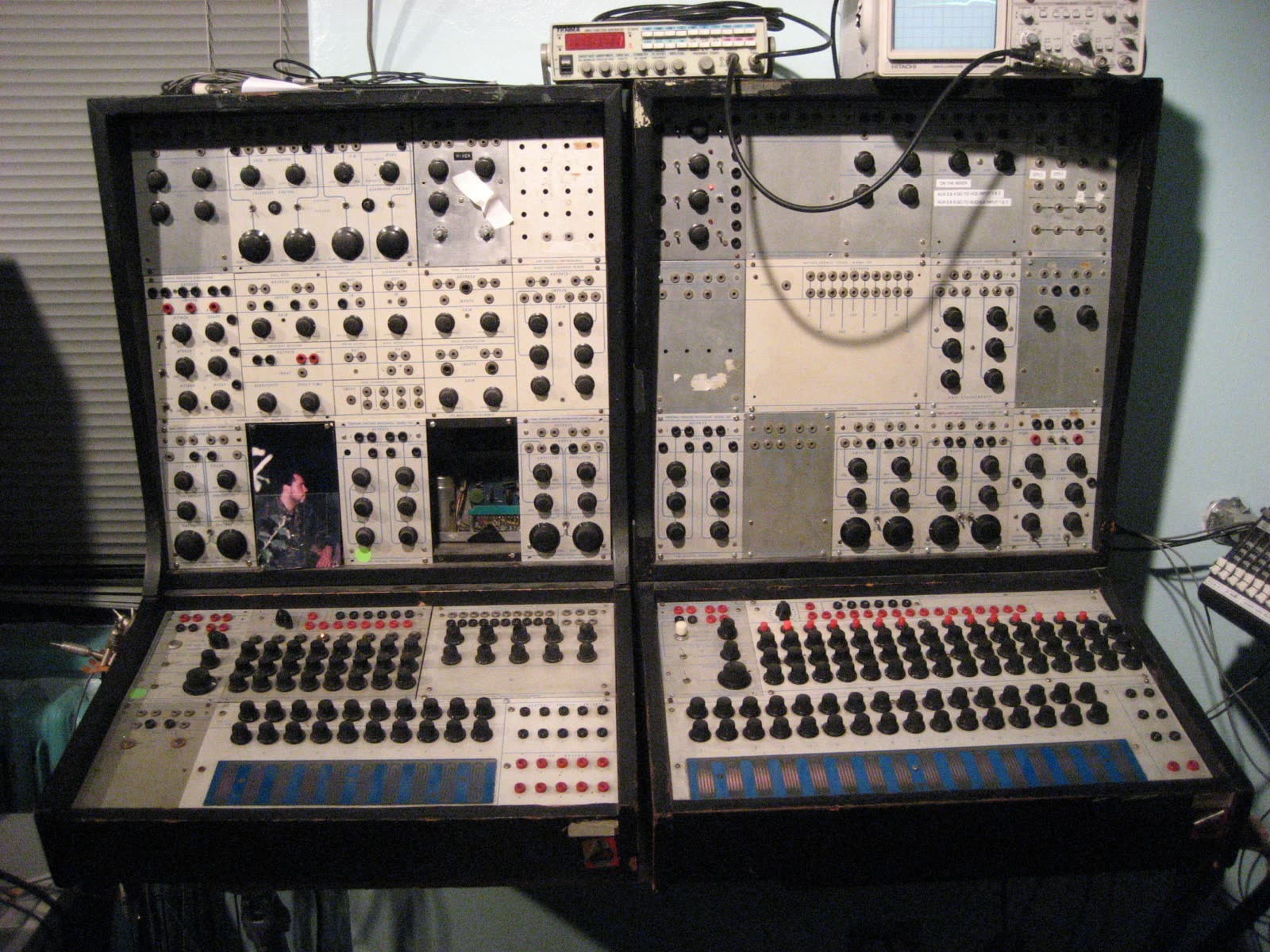 Two cabinets of a Buchla 100 series modular synthesizer covered in knobs, jacks and patch points