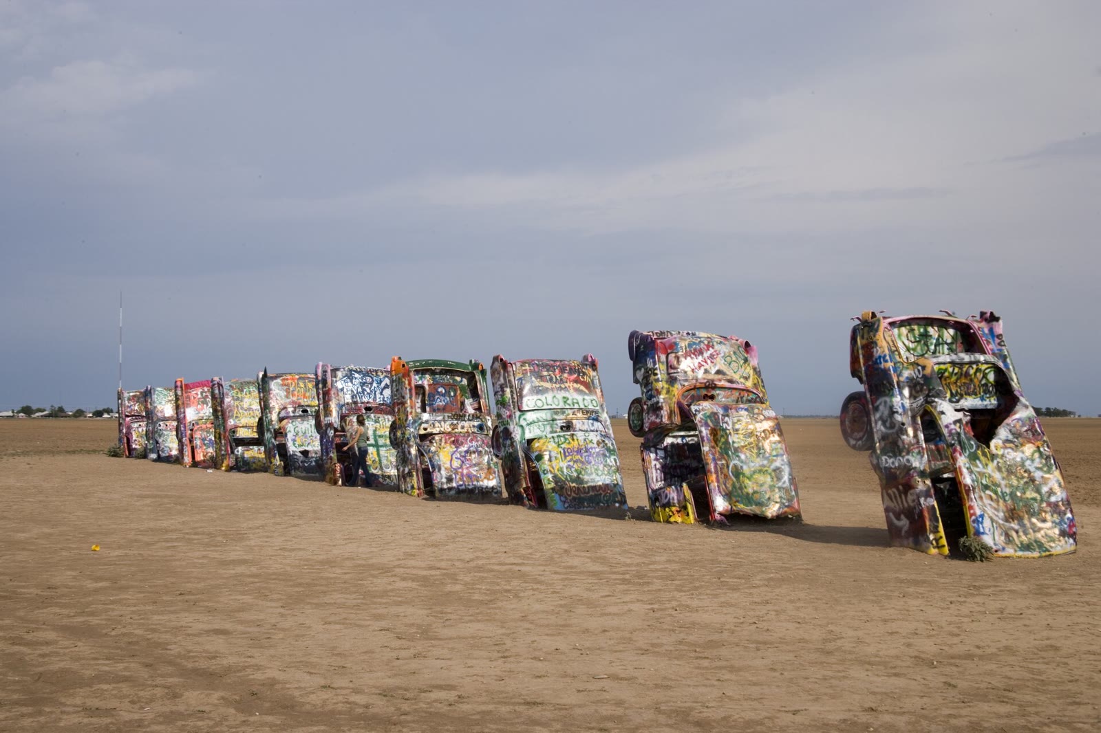 Graffiti-covered Cadillacs buried nose-down in a row in a field beside Route 66 near Amarillo