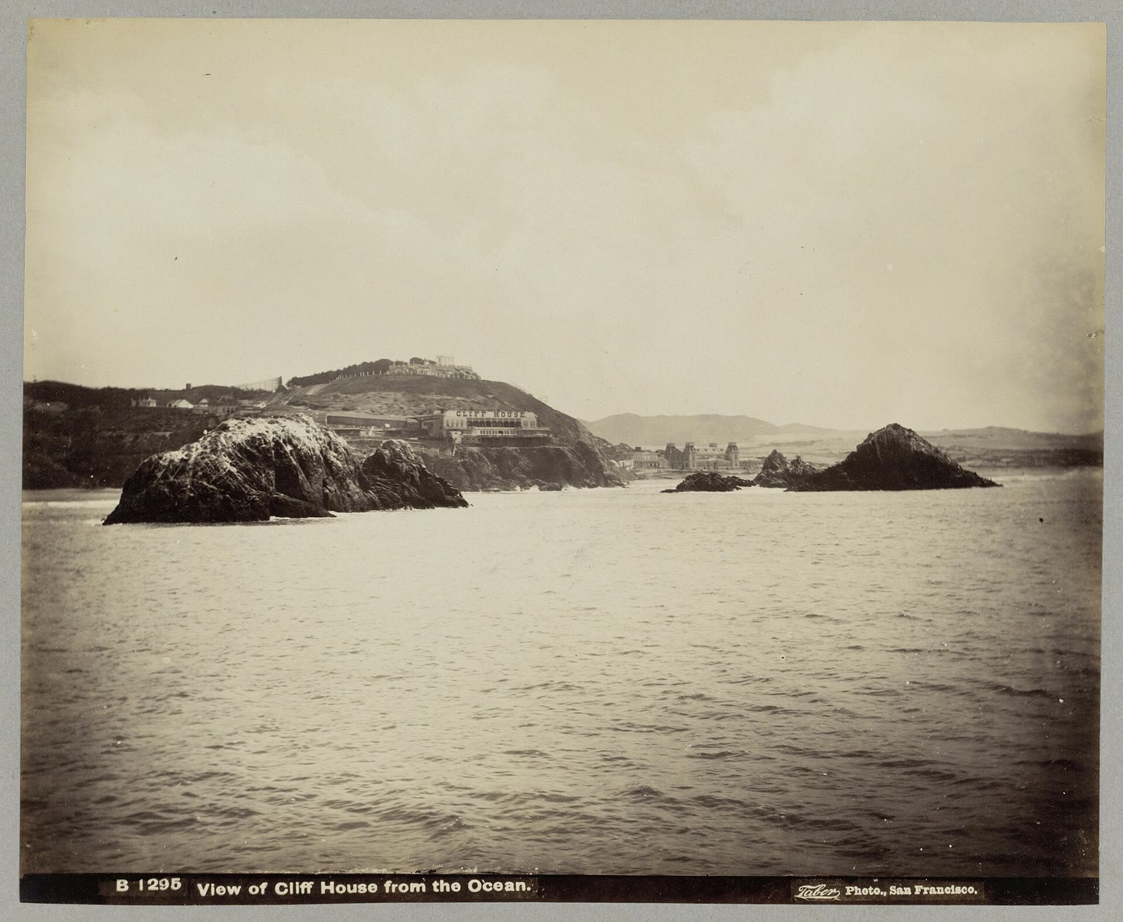 Nineteenth-century photograph of the Cliff House on its rocky point, seen from the ocean