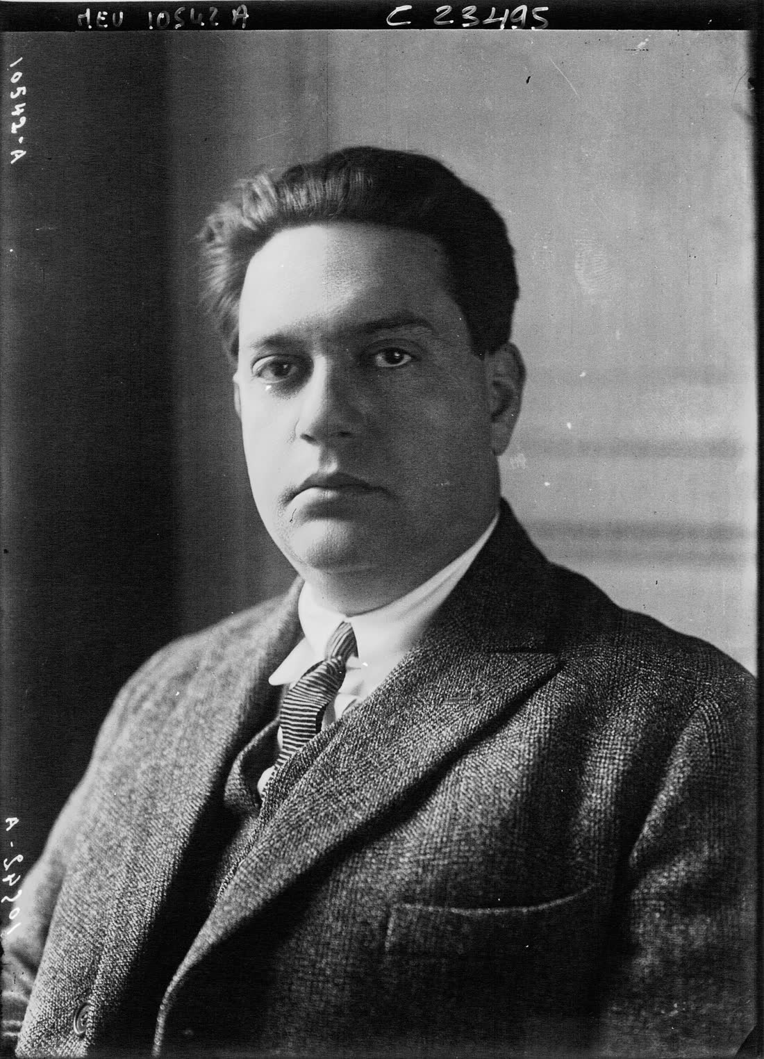 Black and white studio portrait of the young composer Darius Milhaud in a tweed jacket and tie