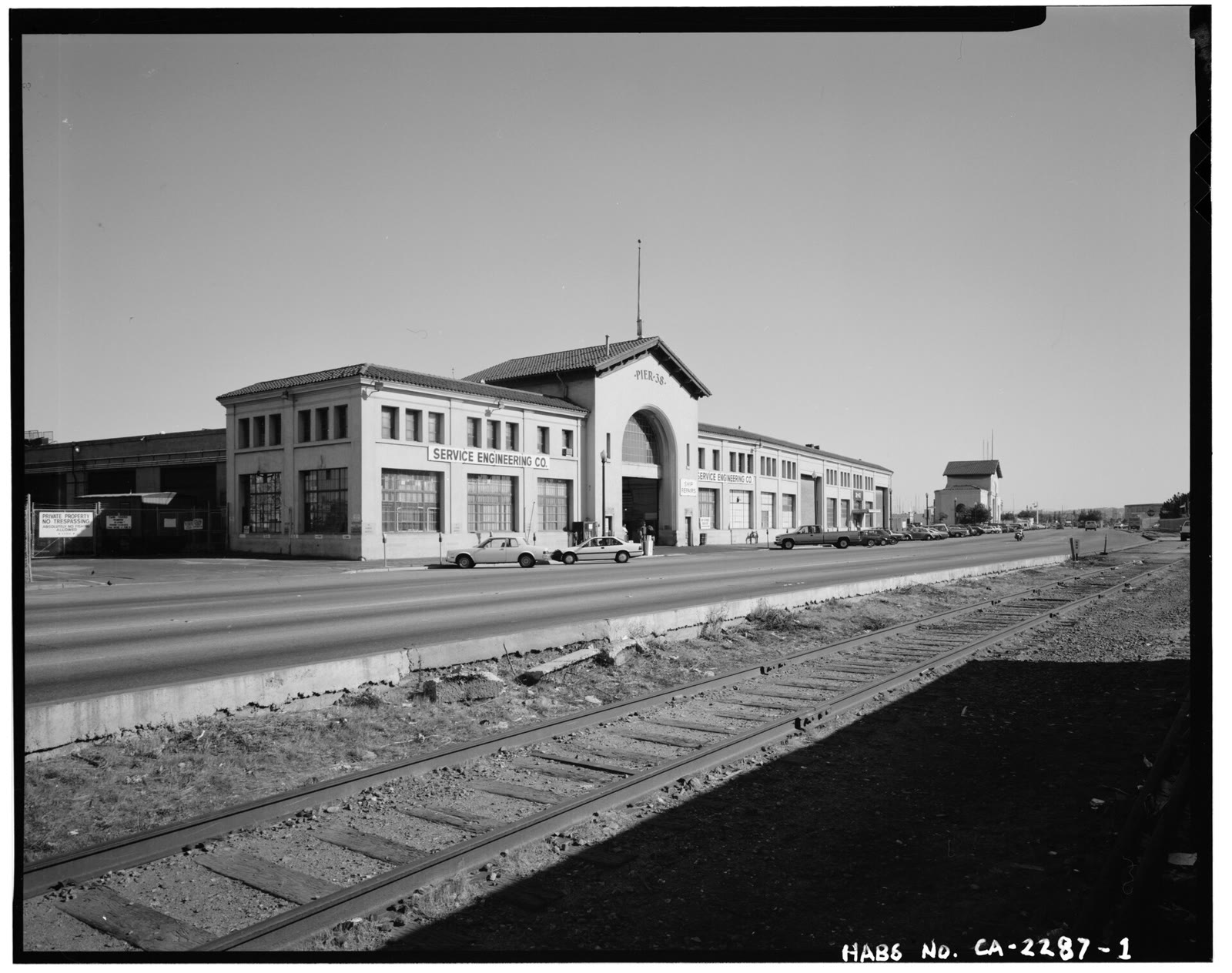 Black-and-white survey photo of the Pier 38 and 40 bulkhead buildings on the Embarcadero with railroad tracks in front
