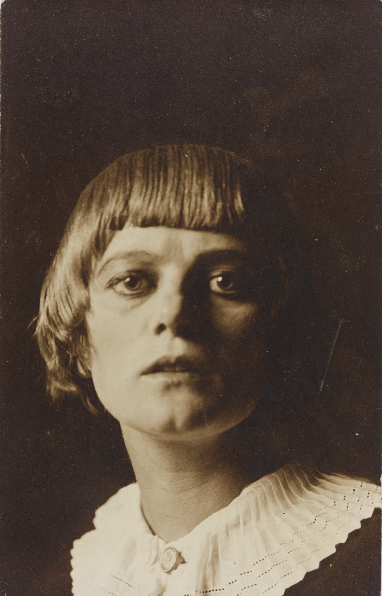 Sepia portrait of a young Emmy Hennings with a short fringe and a white lace collar