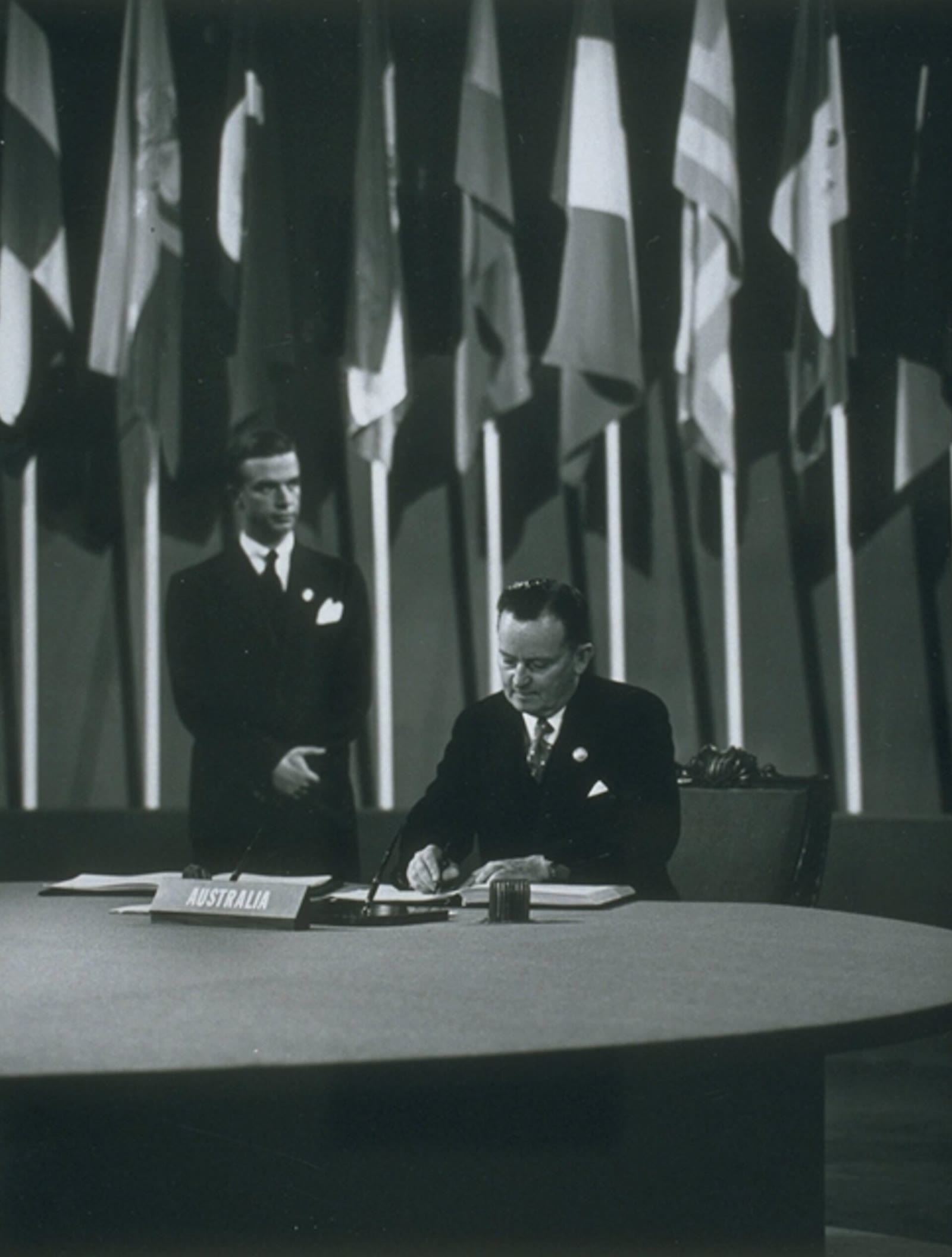 Australian delegate Frank Forde seated at a table, signing the United Nations Charter in 1945