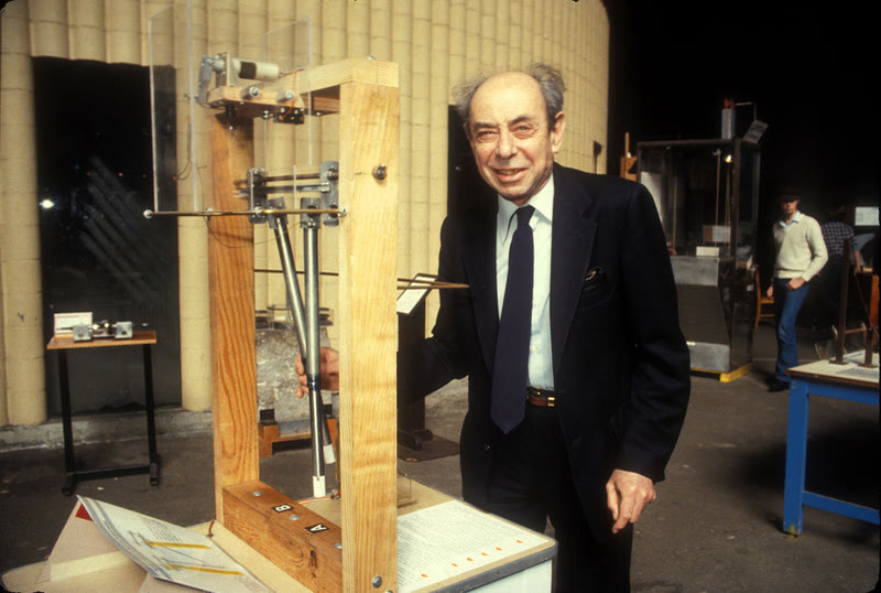 Physicist Frank Oppenheimer standing beside the Coupled Pendulums exhibit at the Exploratorium
