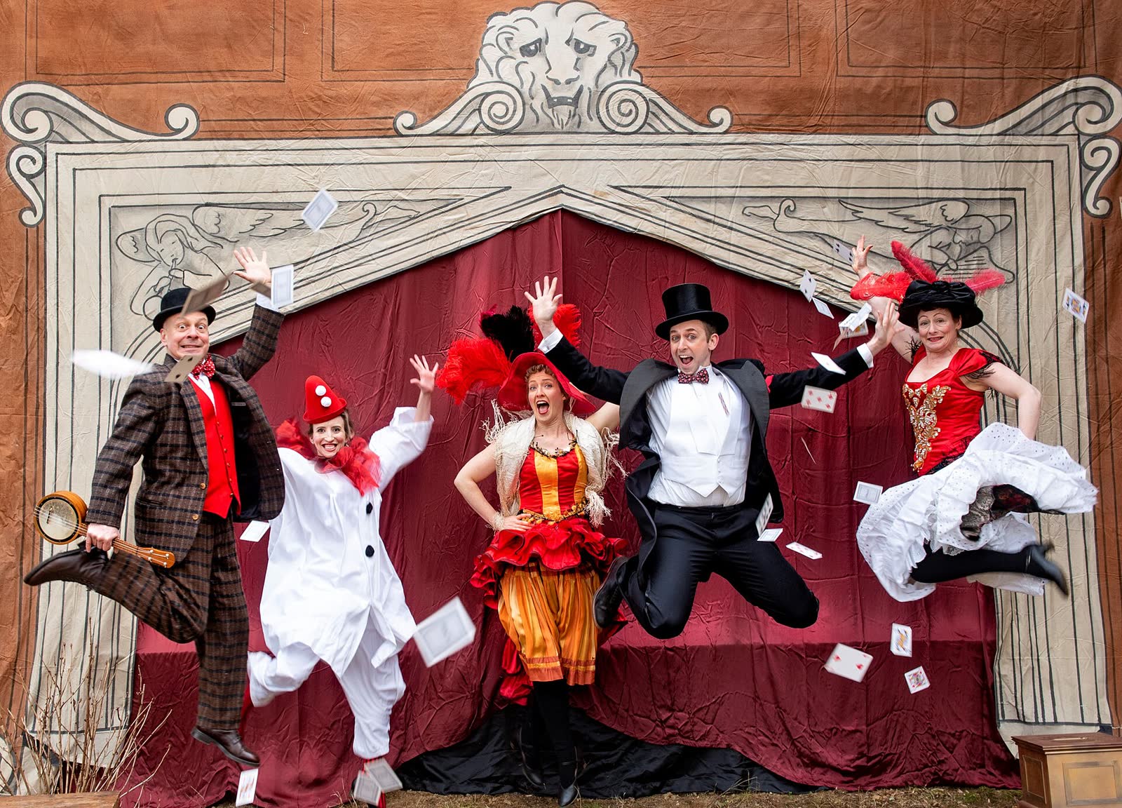 The five members of Happenstance Theater jumping in the air together in vaudeville costumes