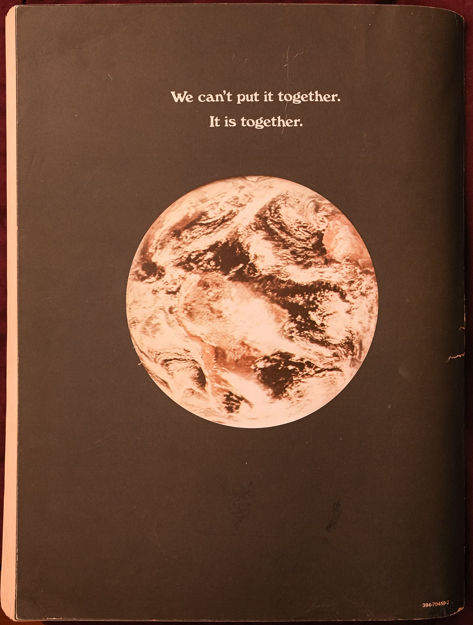 Black back cover of the Last Whole Earth Catalog with a photograph of the whole Earth and a two-line motto
