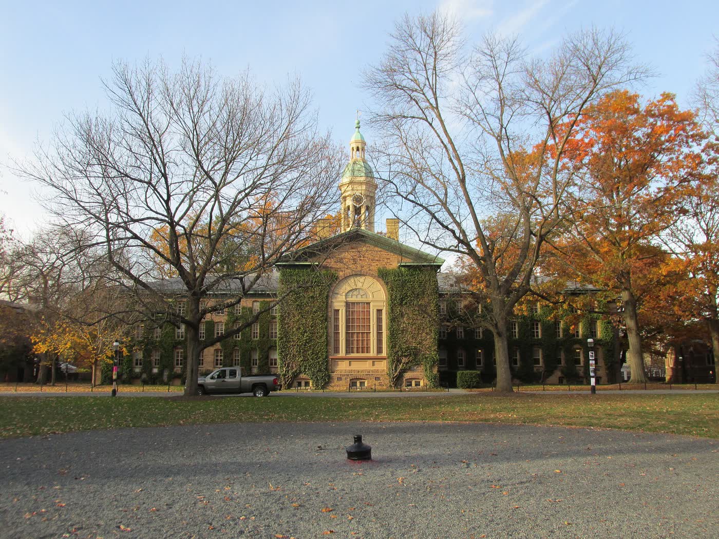 Nassau Hall at Princeton, a stone building with a cupola, seen across a lawn with autumn trees