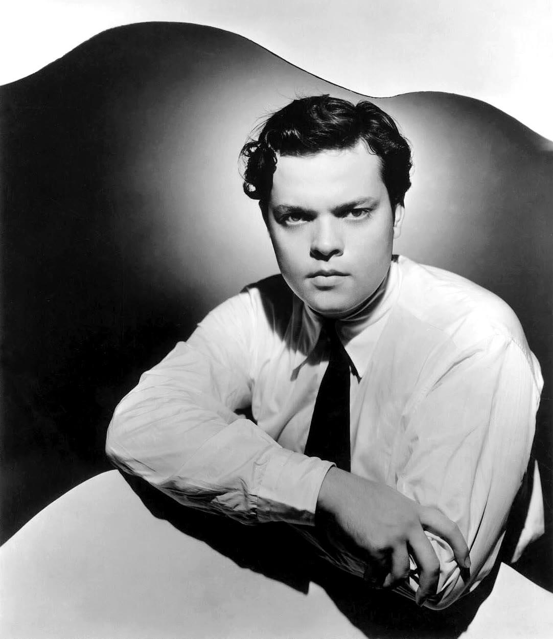 Studio portrait of a young Orson Welles in shirt and tie, arms folded