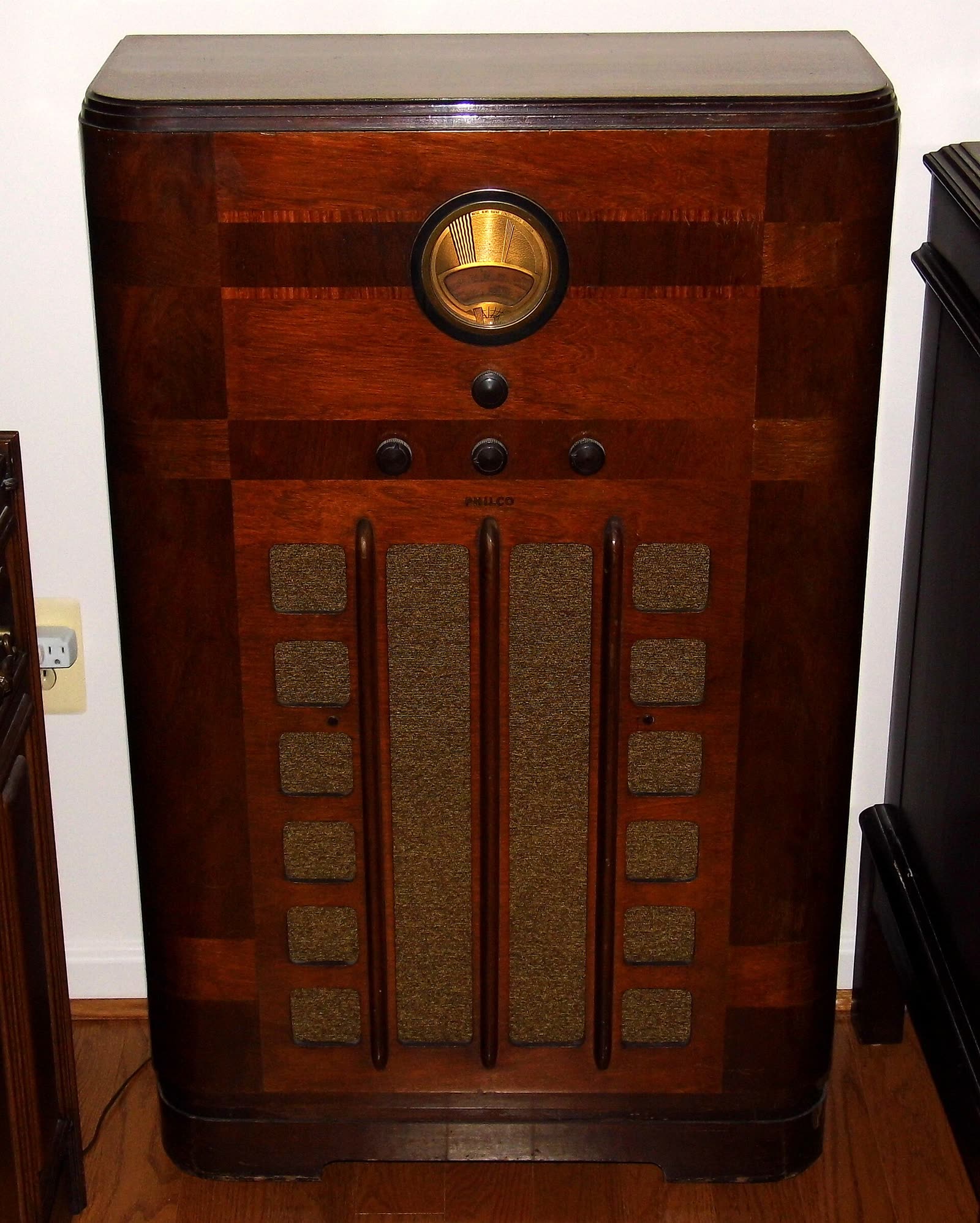 Tall wooden Philco console radio cabinet with a round dial and speaker grille