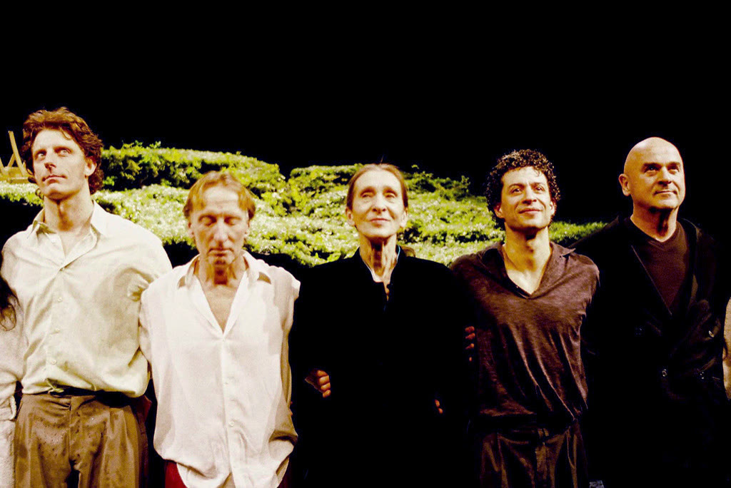 Choreographer Pina Bausch standing among her dancers on stage after a performance of Wiesenland