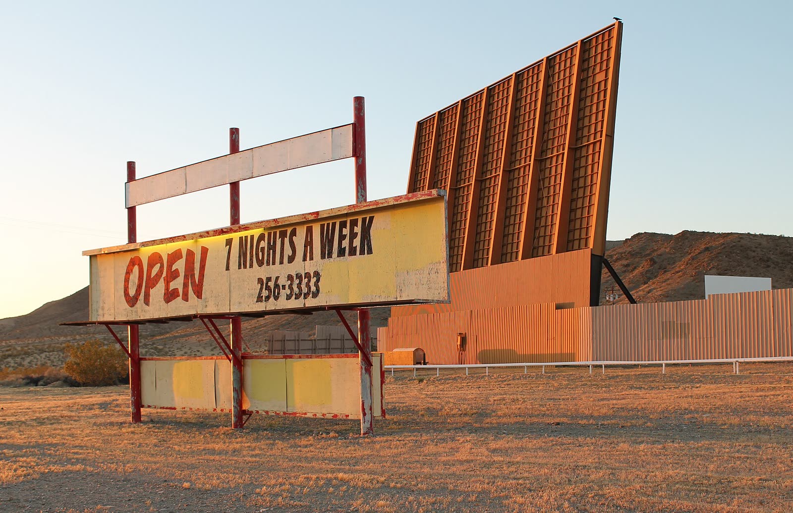 The Skyline Drive-In marquee lined up with its orange main screen and second screen in Barstow, California, at sunset
