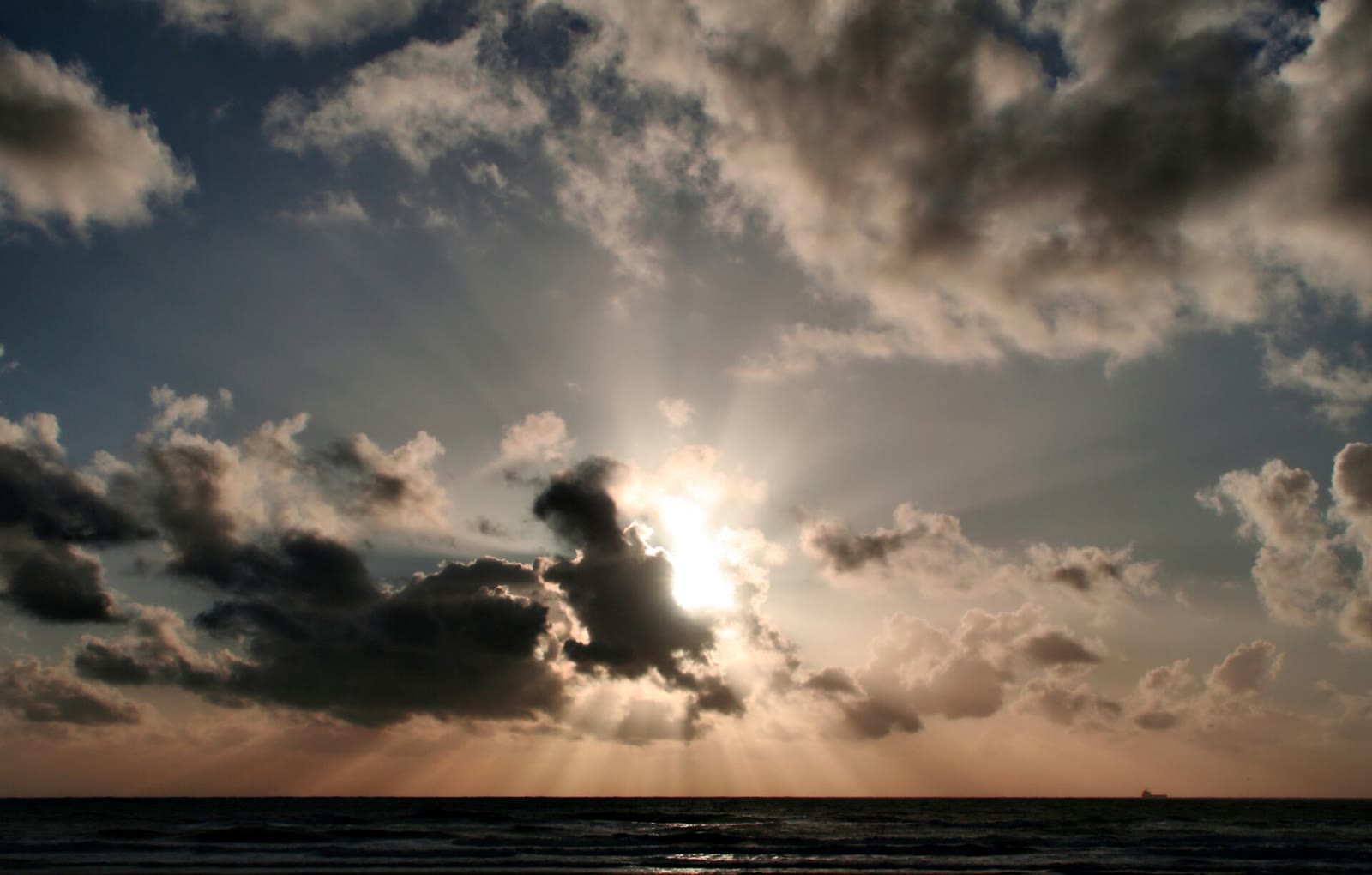 Shafts of sunlight breaking through clouds over the Pacific Ocean at sunset