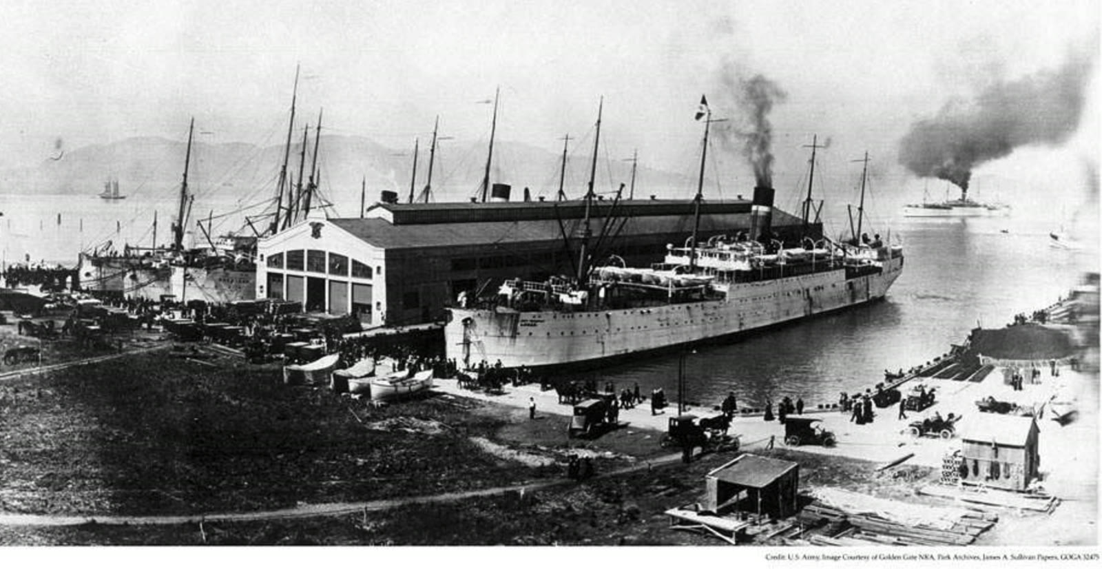 Historic black and white photograph of the army transport ship USAT Logan moored alongside Pier 2 at Fort Mason