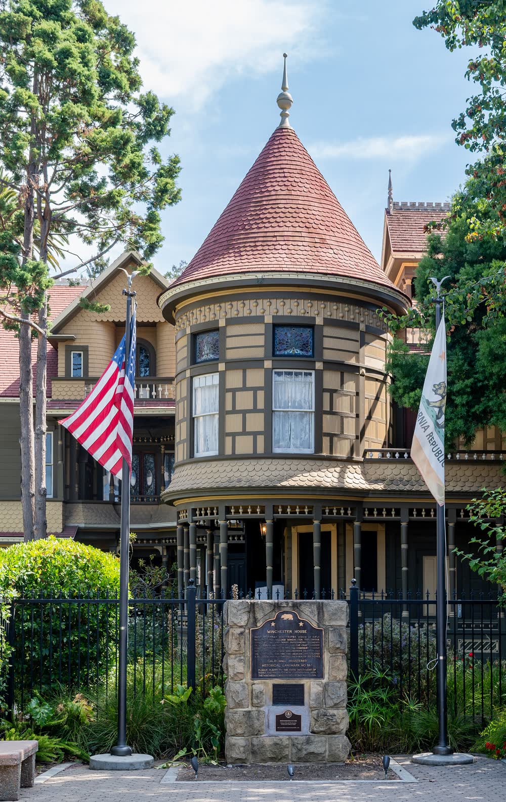 Round turret with a red conical roof rising above the timber and shingle walls of the Winchester house