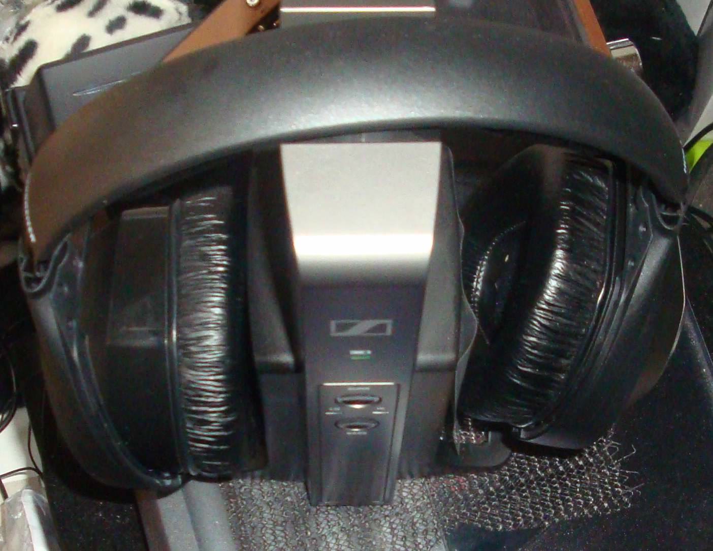 A pair of over-ear wireless headphones resting on their radio transmitter base