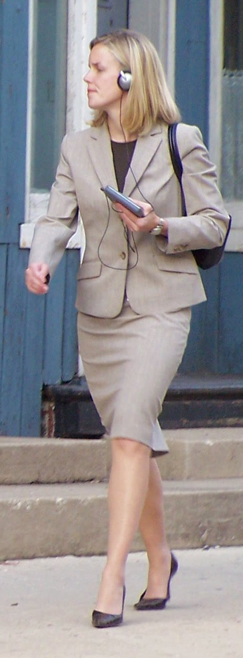 A woman walking along a city street while listening to a Walkman on headphones