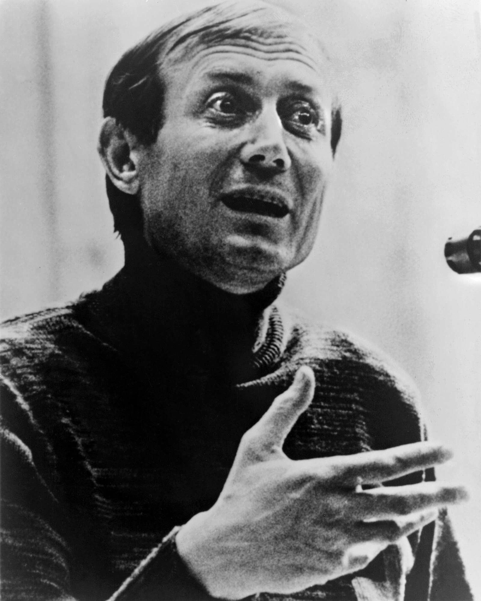 Black and white portrait of the poet Yevgeny Yevtushenko gesturing as he speaks into a microphone